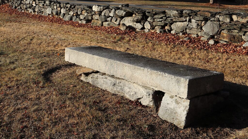 Panca di pietra addossata al muro di un chiostro, con colonne e archi che si aprono sul cortile