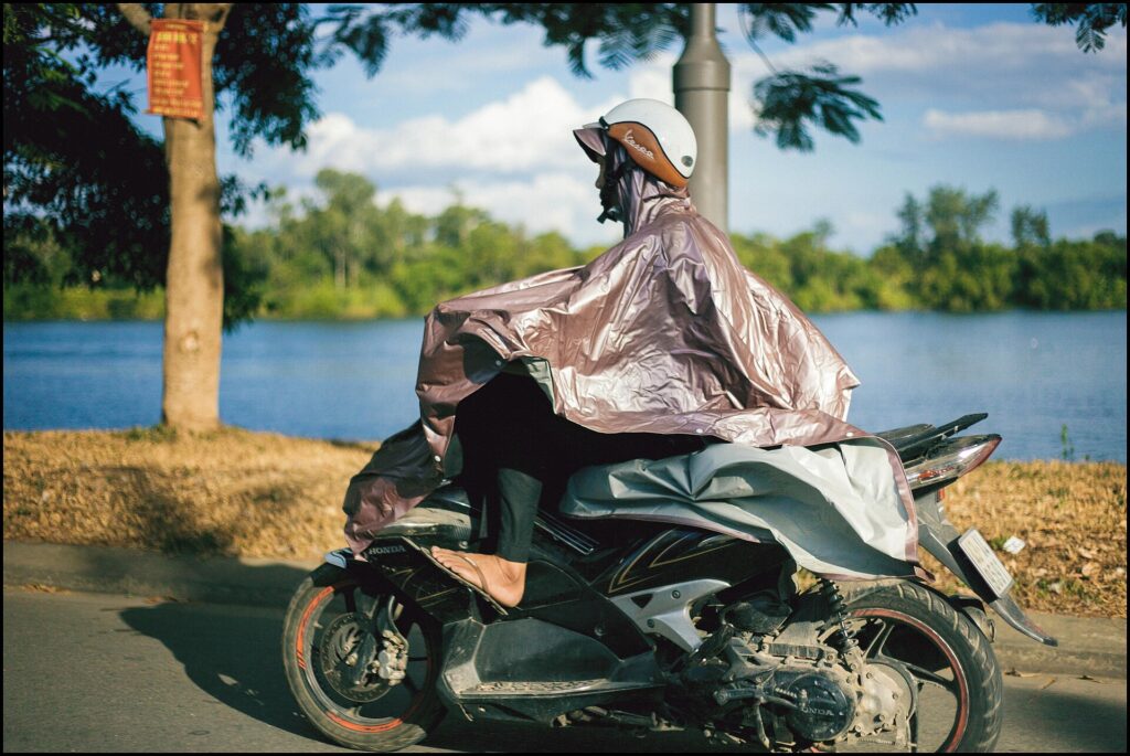 Camminatore con mantella impermeabile che copre anche lo zaino, su un sentiero bagnato
