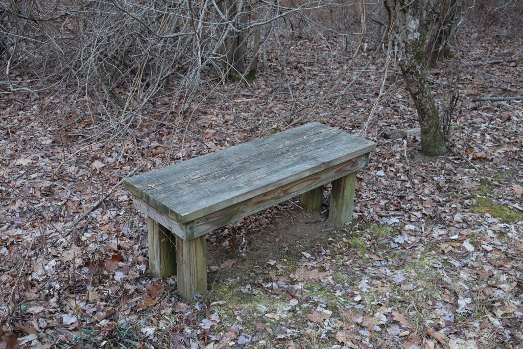 Palo di legno con frecce segnavia all'incrocio di due sentieri fra i prati di collina