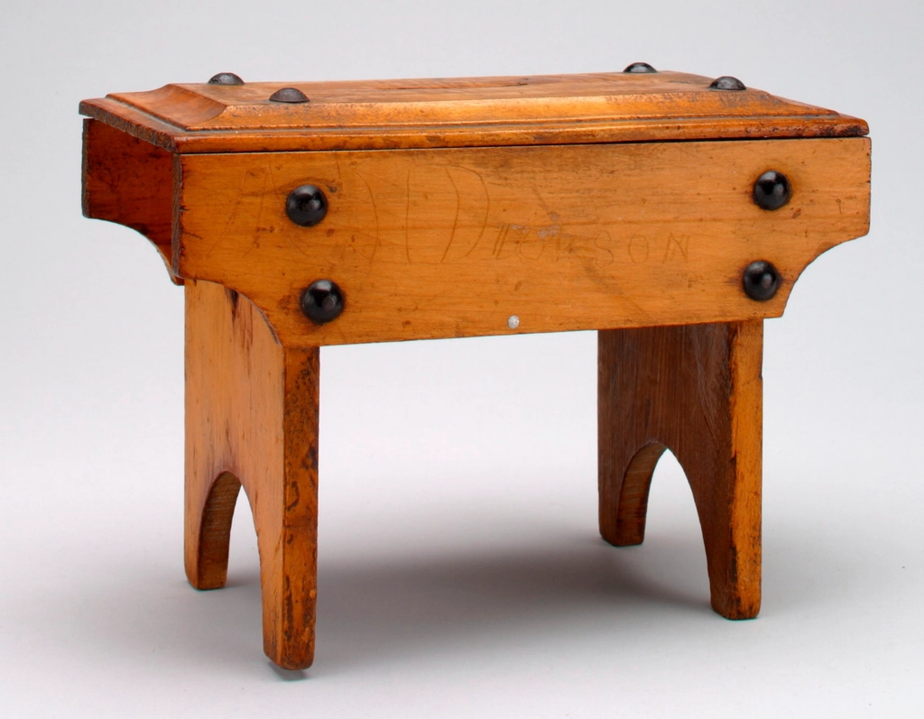 Alcune monete sparse su un piano di legno chiaro accanto a una piccola scatola aperta