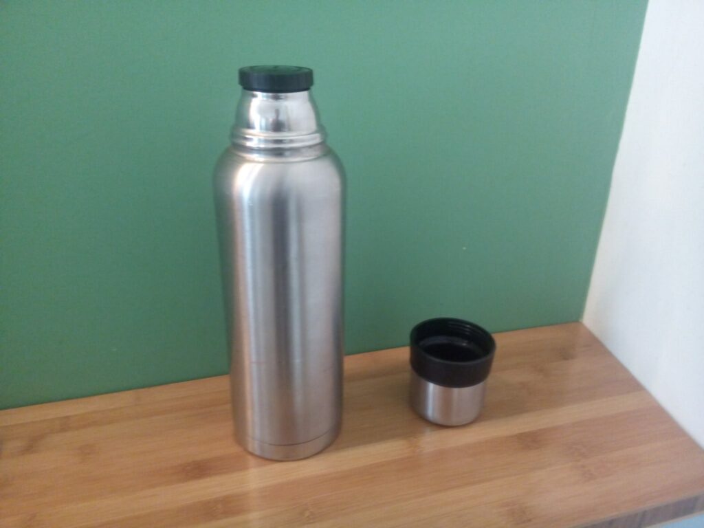 Thermos e coperta di lana appoggiati su una panca di legno prima di una veglia